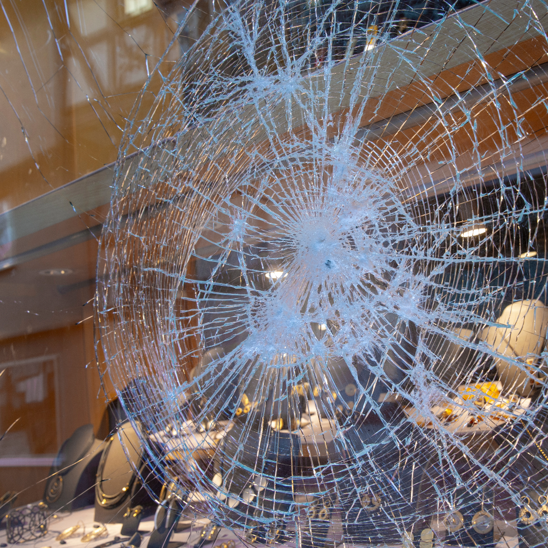 Broken glass with a spider web pattern at jewelery store stuck together with window tint film