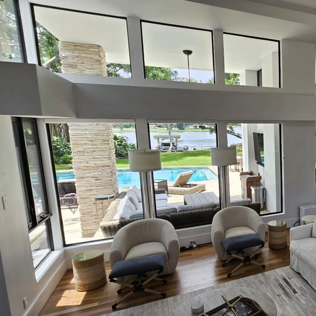 Modern living room with large windows overlooking a pool and garden window film to keep the view but block the harsh light and heat